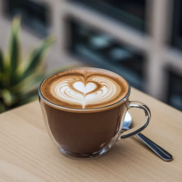 Grande tasse de cappuccino avec un cœur en mousse de lait Café expresso surmonté d'une micro-mousse au cœur Boisson chaude servie dans une tasse en verre transparent Détail d'une tasse de café avec une décoration en cœur